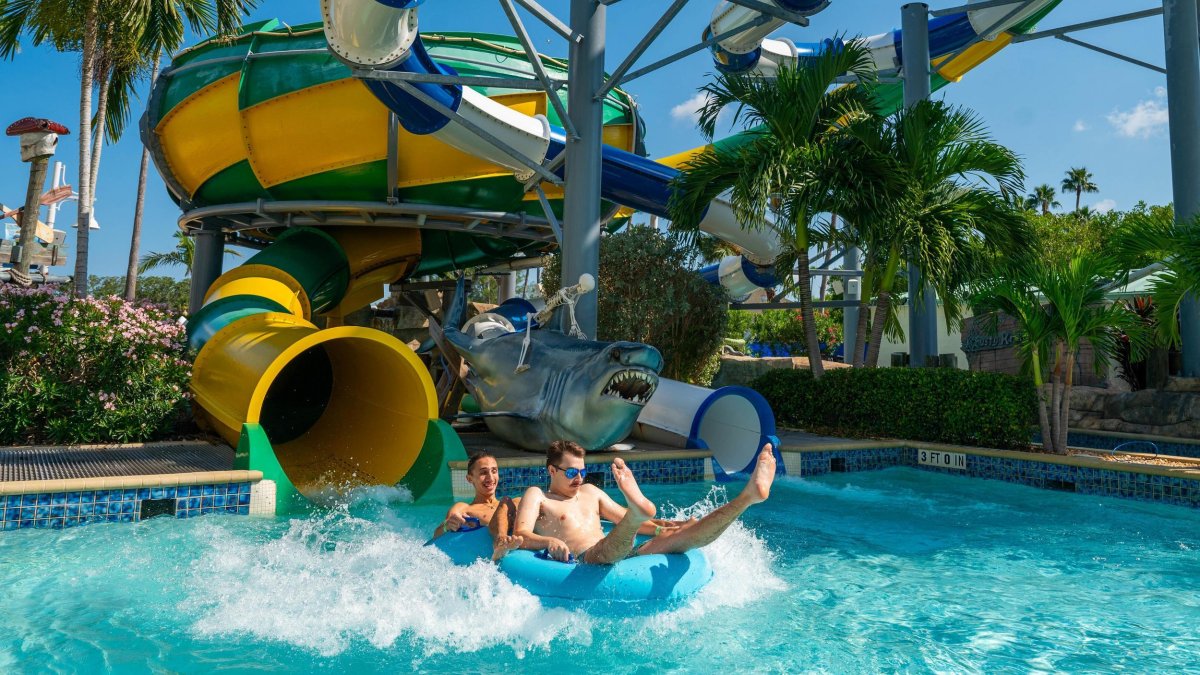 two people in inner tubes splash down into a pool from a twisty water slide at Splash Harbour Water Park