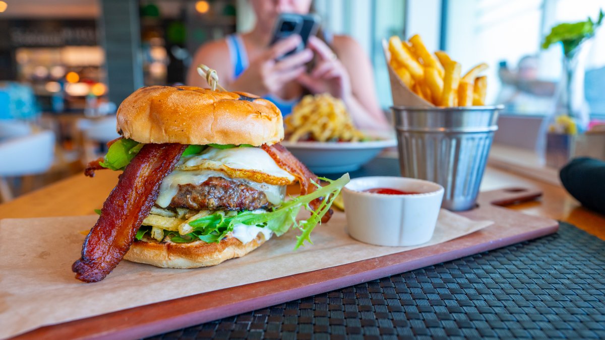 a big juicy burger with cheese and bacon on a wooden board with a metal bucket full of fries at BRGR Kitchen & Bar in Treasure Island