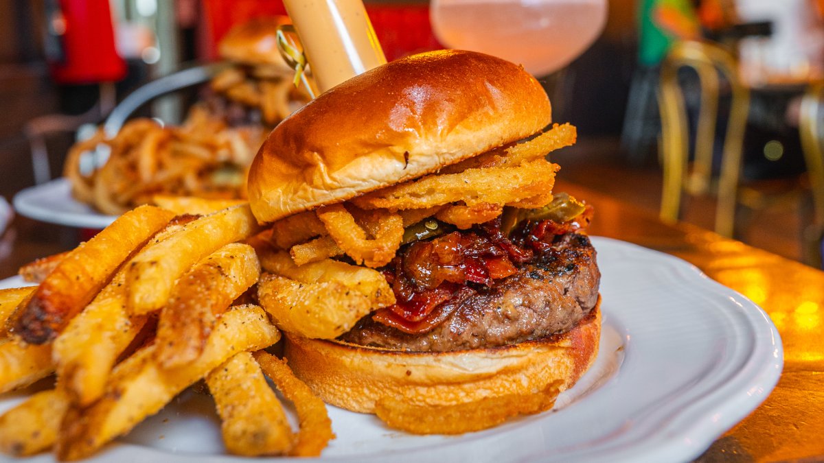 a burger with bacon and onion rings on top with a side of crispy fries at Gigglewaters