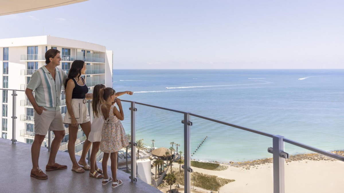 a mom, dad and two little girls on a balcony overlooking the Gulf at Opal Sol resort