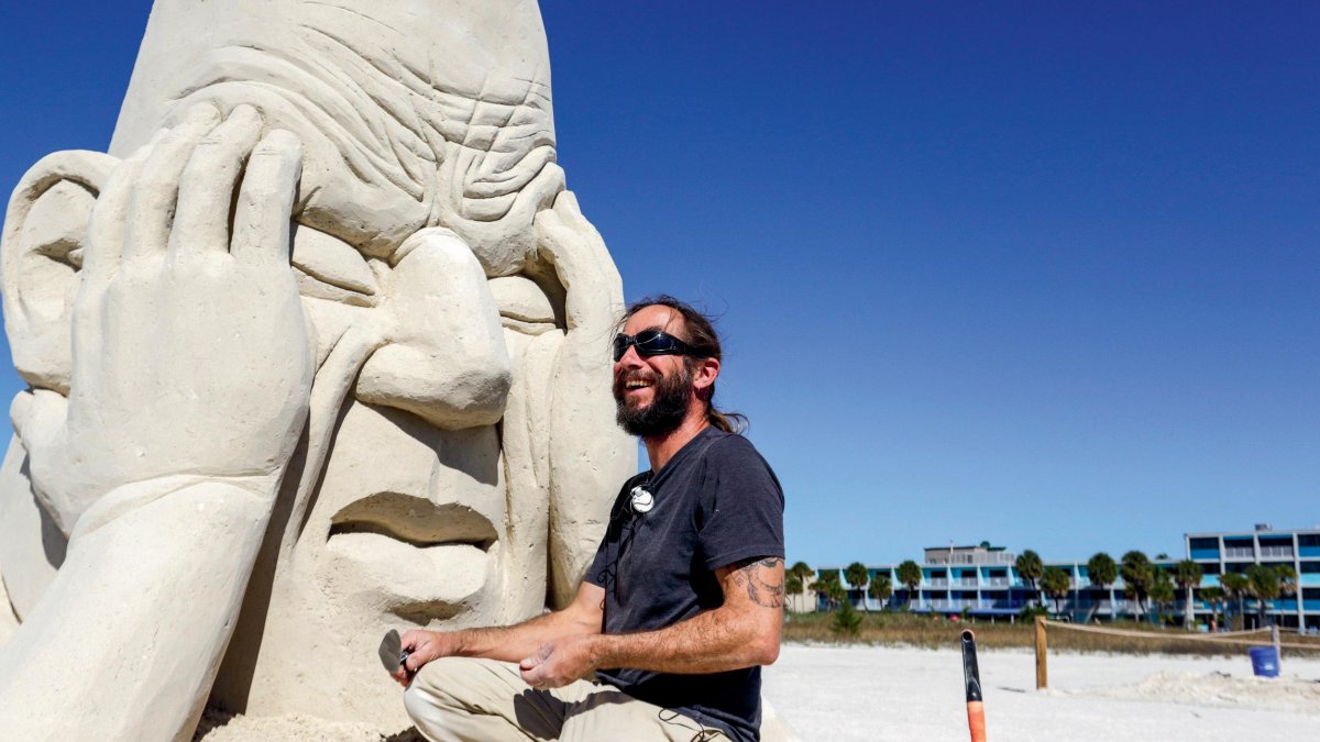 a sculpture working on a sand sculpture of a giant head at Sanding Ovations