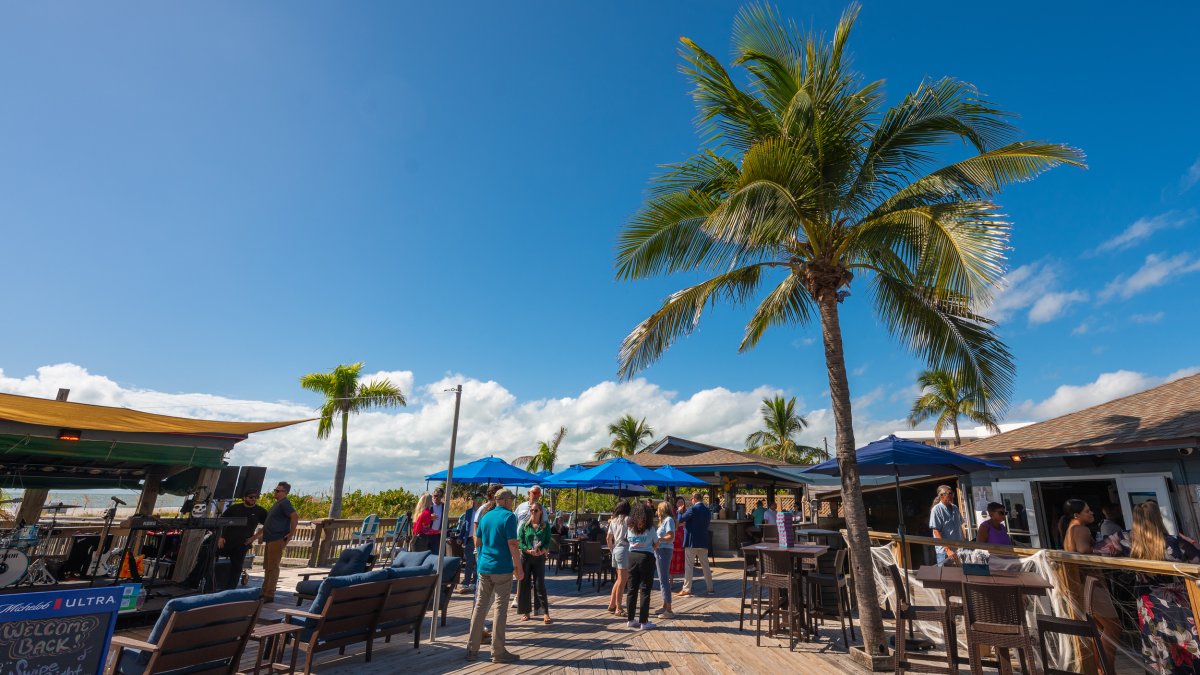 an outdoor bar area next to the beach and palm trees