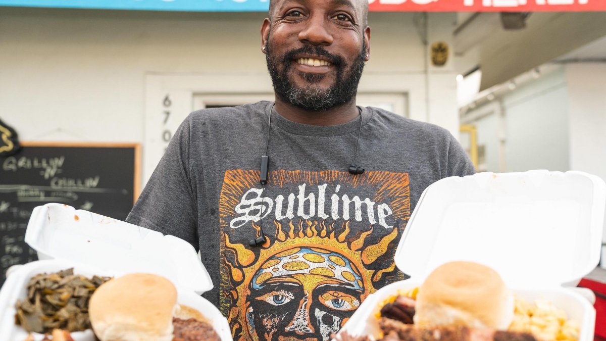 A man holding to-go boxes of hearty dishes outside Grillin' & Chillin' in Florida.