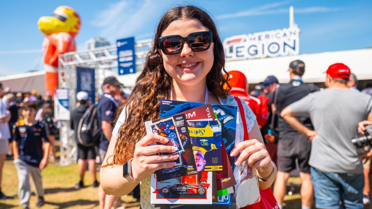 a smiling fan holding "swag" collected at the fan village at the Firestone Grand Prix