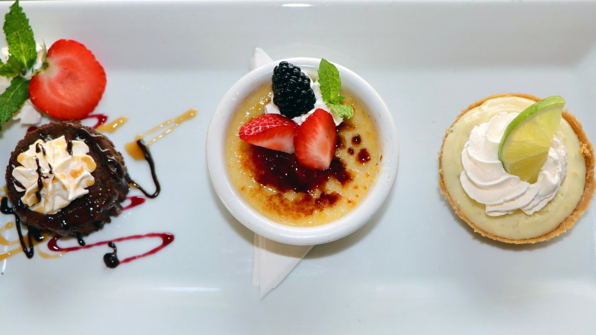 a white dish with three mini desserts including a flourless chocolate cake, a creme brulee and a key lime pie at Island Way Grill