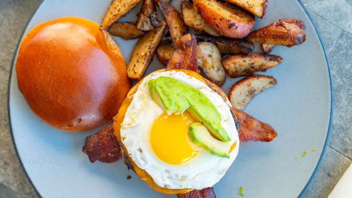 a sunnyside egg with avocado on a brioche bun next to thick potato wedges at Clear Sky Cafe in Clearwater FL