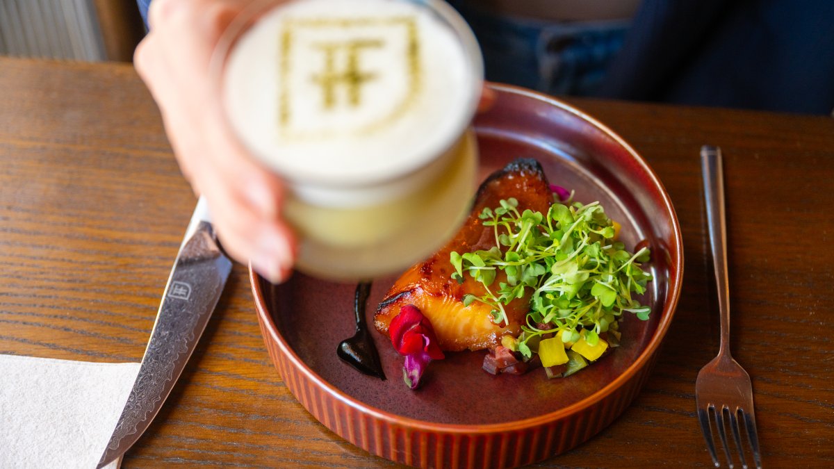 a plate of miso black cod and someone's hand holding an elegant cocktail at Fortu in St. Pete
