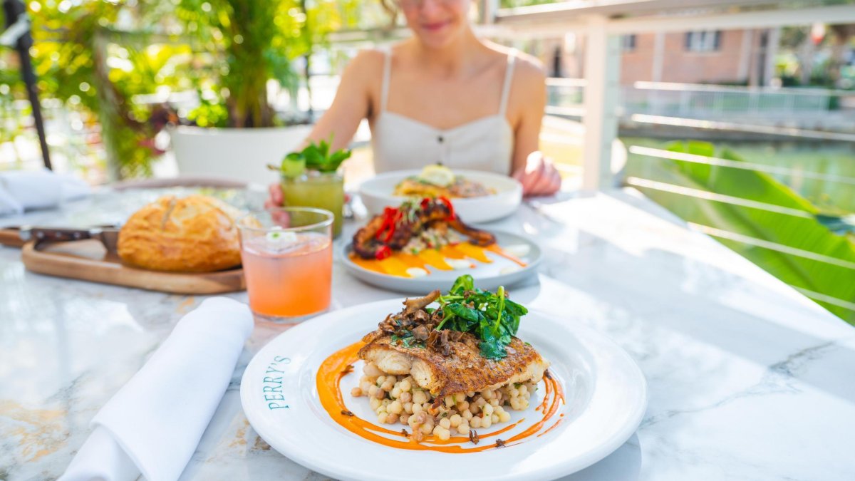 a woman dines outside at Perry's porch with lush greenery near the table