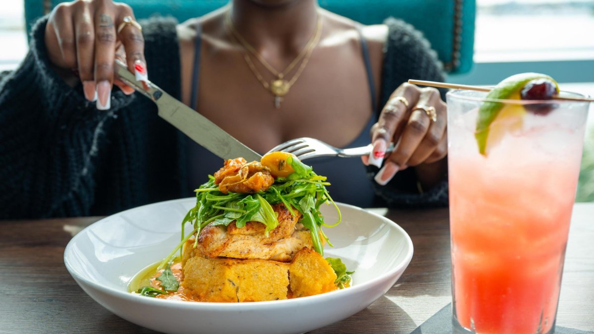 a woman begins to eat a plate of fish stack high with garnishes at Teak at the St. Pete Pier