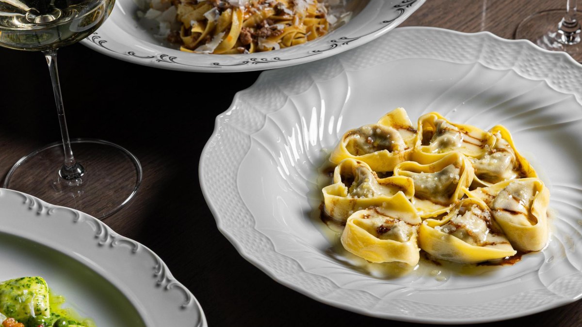 several different pasta dishes and a glass of wine on a table at Elliott Aster in St. Pete
