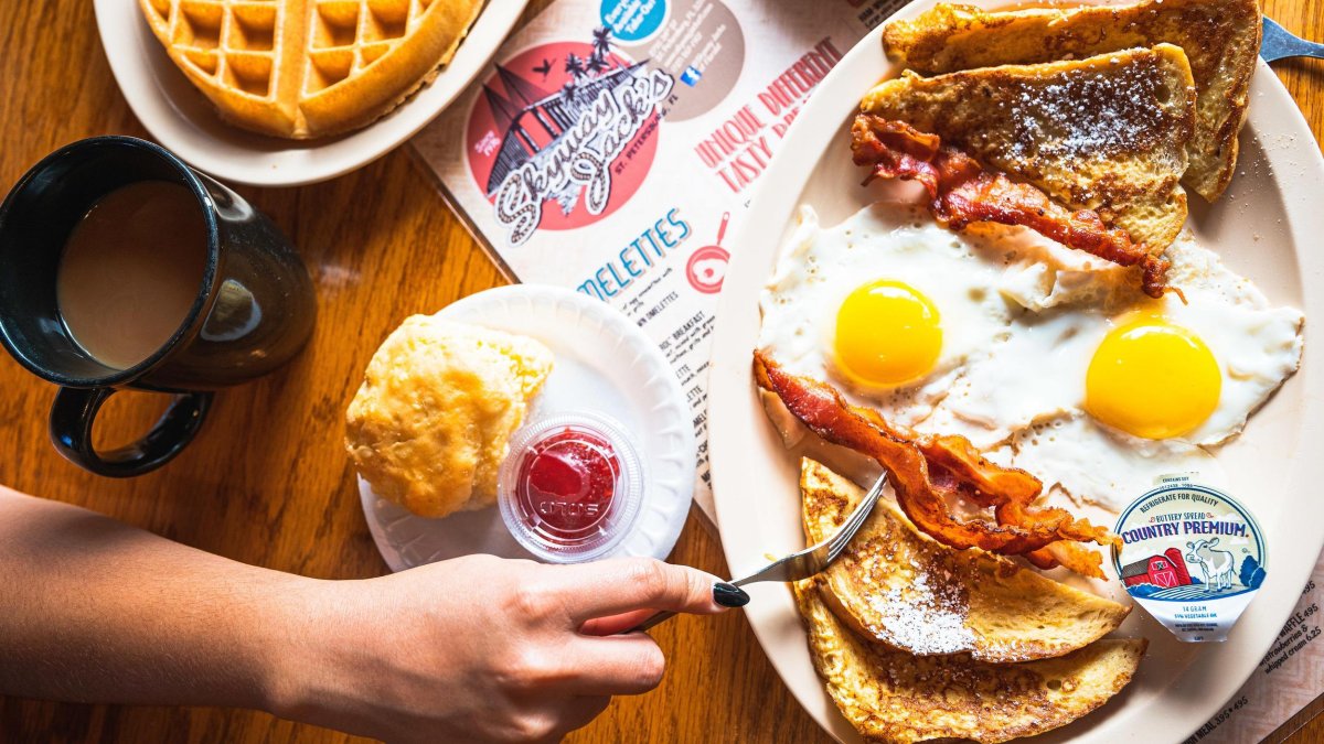 a table with bacon and eggs, biscuits, waffles and coffee at Skyway Jack's in St. Pete
