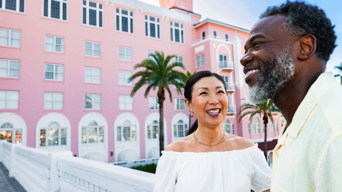 a smiling couple standing outside the legendary Don CeSar hotel in St. Pete Beach