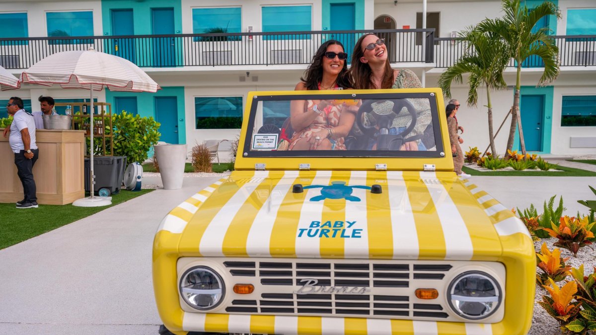 two women sit in a playful yellow and white striped car at The Luce hotel in St. Pete Beach