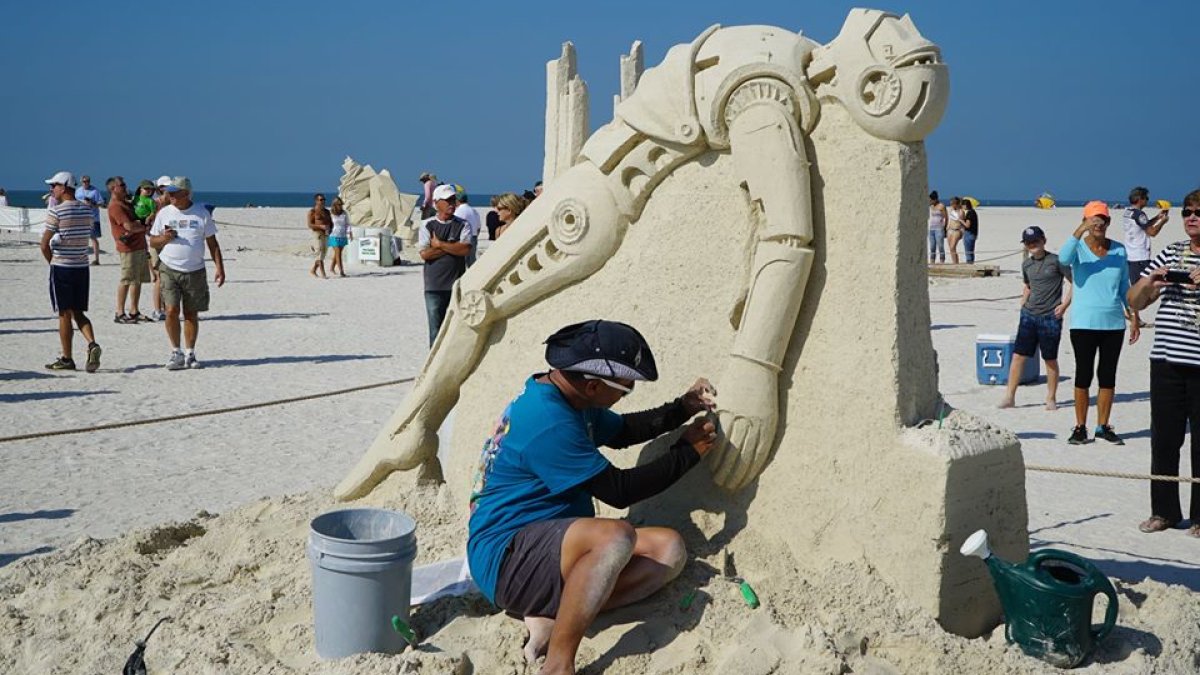 Artist on the beach making a sand sculpture