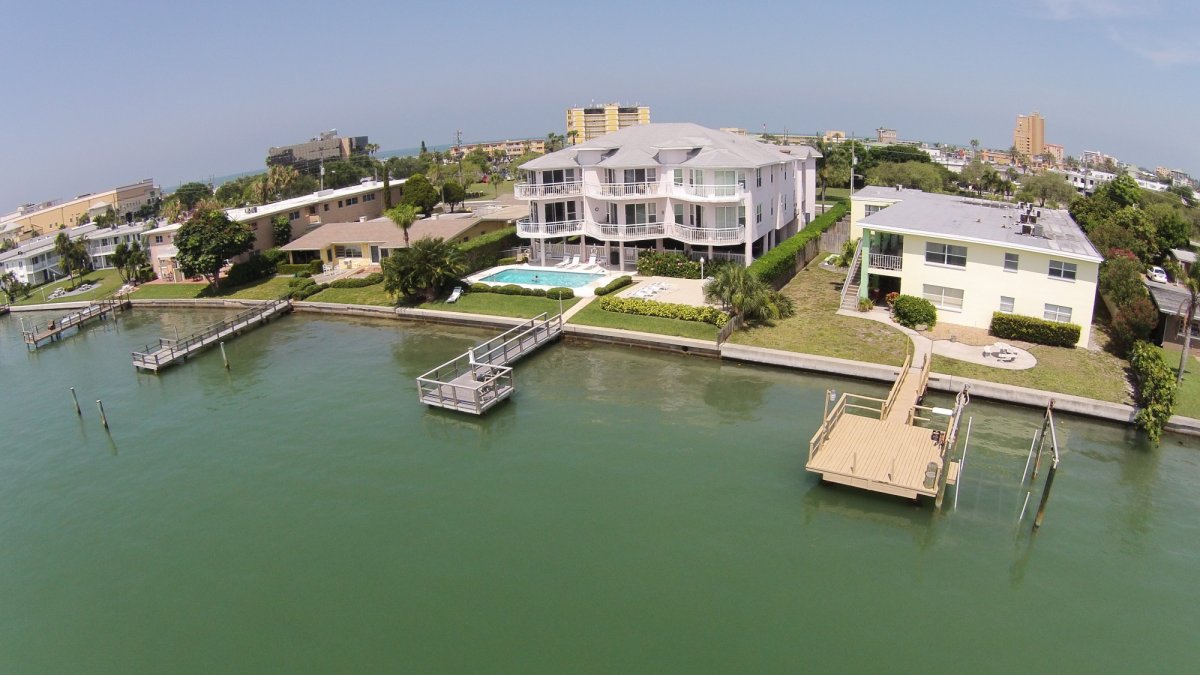 A 2-story waterfront condo building with a pool and parking beneath