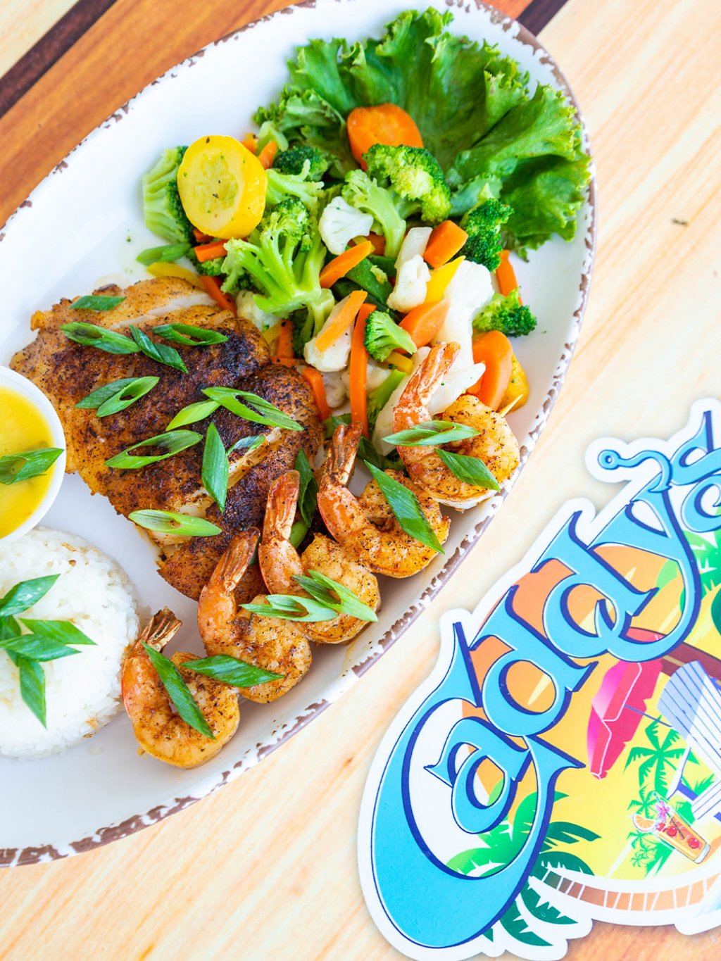 blackened shrimp and grouper are on an oval-shaped plate along with fresh veggies