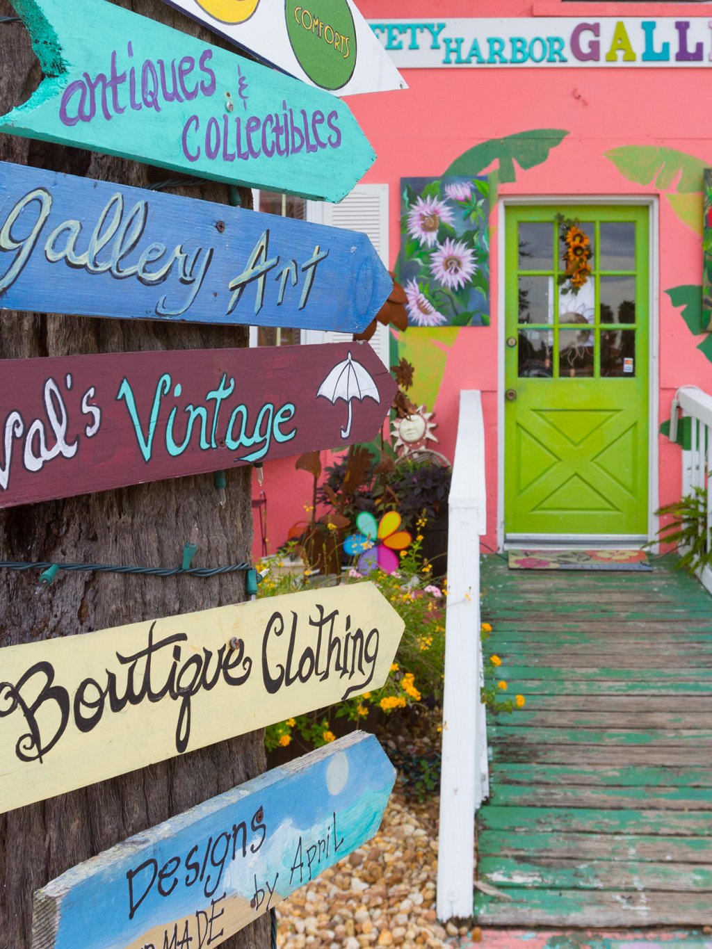 Colorful signs in front of the pink wall of the Safety Harbor Galleria, a gift shop and gallery