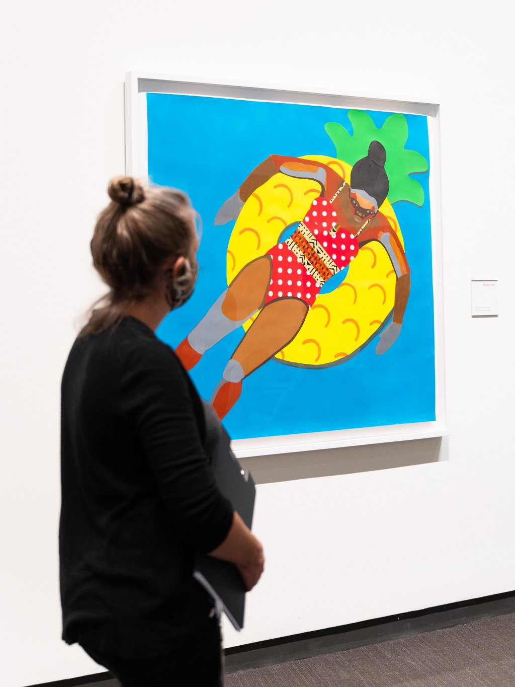 Una mujer viendo una pintura de una persona flotando en una piscina.