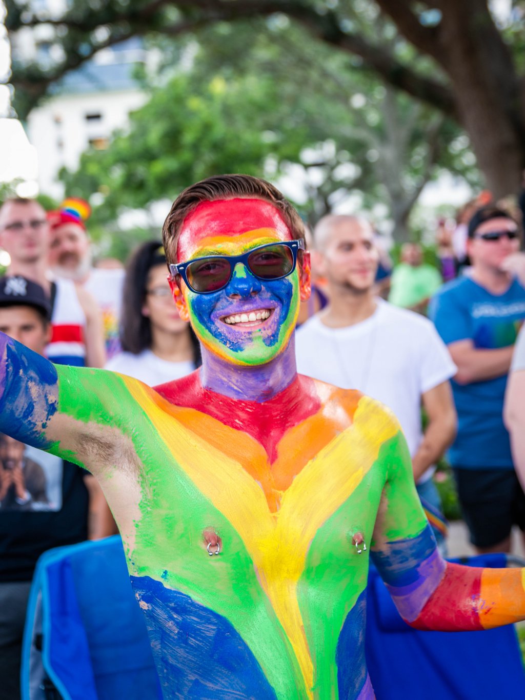 A shirtless man with chest and face painted in rainbow colors during St. Pete Pride.