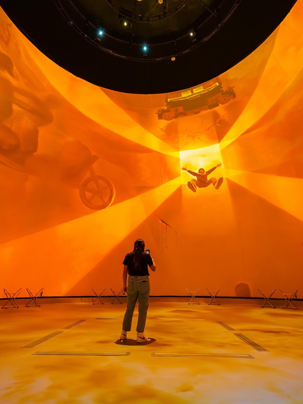 a young woman stands in the middle of a multi-media experience in the Dali Dome at the Salvador Dali Experience