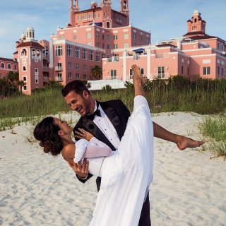 A groom sweeps up his bride in front of the Don CeSar