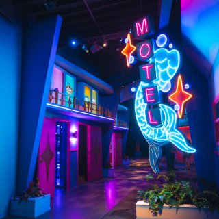 A neon sign outside an artistic replica of a vintage Florida hotel
