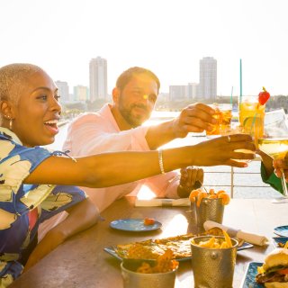 a group of friends toasting with drinks at Pier Teaki at the St. Pete Pier