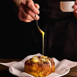 a chef drizzling a bechamel sauce on top of a popover