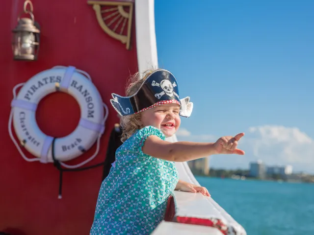A happy little girl wearing a pirate hat on board Captain Memo's Pirate Cruise.