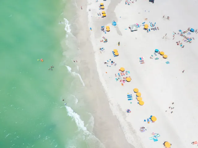 Aerial view of yellow beach cabanas and emerald-green waters of Treasure Island.