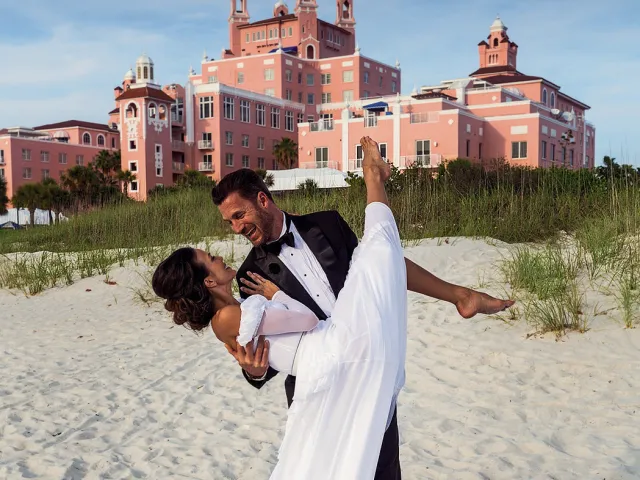A groom sweeps up his bride in front of the Don CeSar