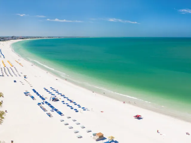 St. Pete Beach aerial panoramic photo showing the entire green waters beach, white sand and lots of hotels cabanas.