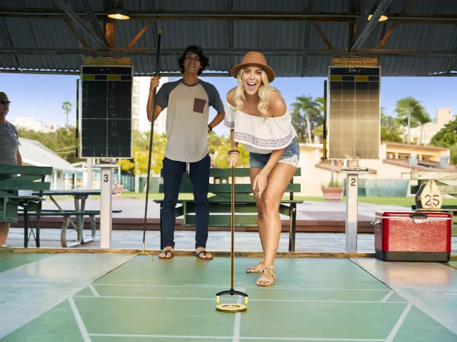 A woman pushes a disc on a shuffleboard at the St. Pete Shuffleboard Club