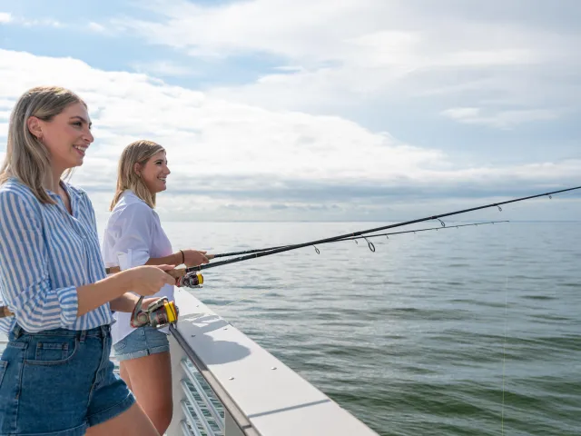 Two caucasian young ladies fishing off of St. Pete Pier.