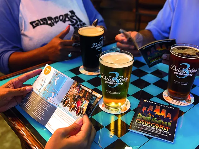 A group of people enjoying beers and reading through the craft beer passport connecting all breweries in Pinellas County.