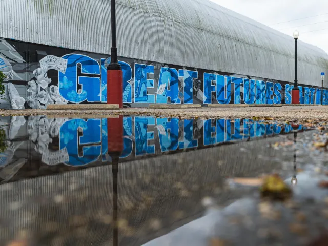 A mural stating "Great Futures Start Here" in blue block letters on the Royal Theater, a WWII era Quonset hut-style building with a metal roof