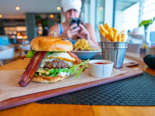 a big juicy burger with cheese and bacon on a wooden board with a metal bucket full of fries at BRGR Kitchen & Bar in Treasure Island