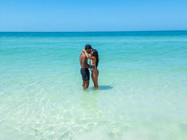 a couple kissing while standing in clear turquoise waters at the beach