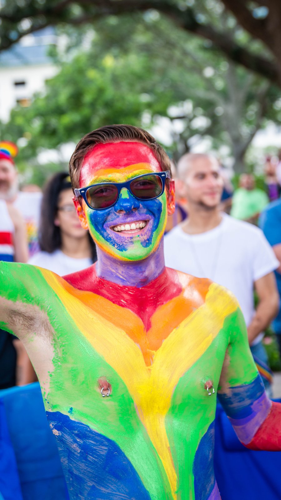 A shirtless man with chest and face painted in rainbow colors during St. Pete Pride.