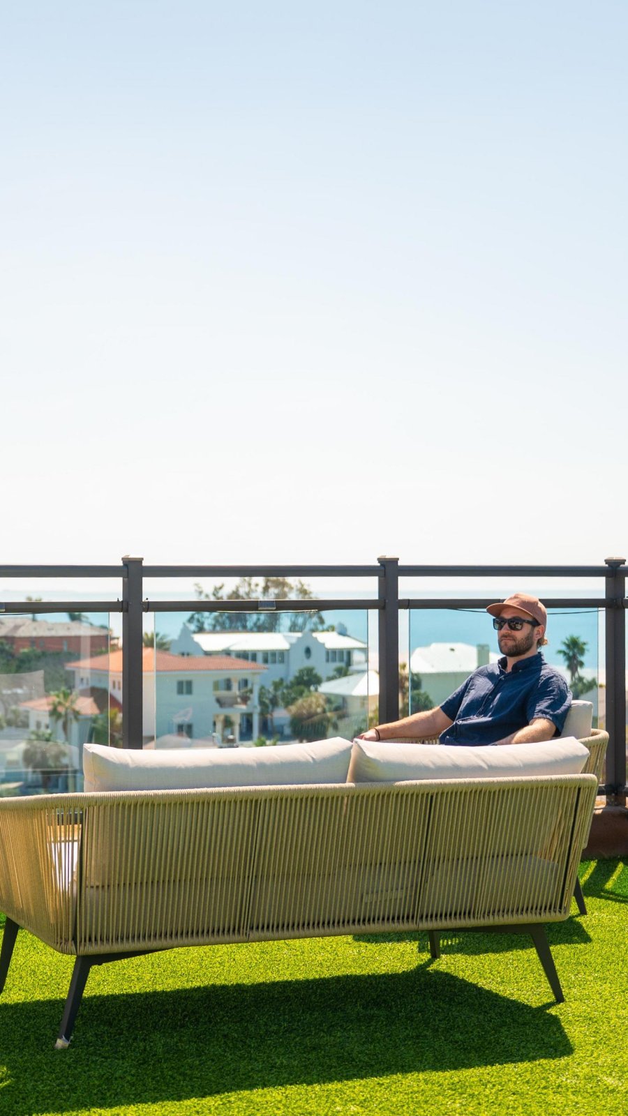 man sitting on rooftop chair with view of city and water
