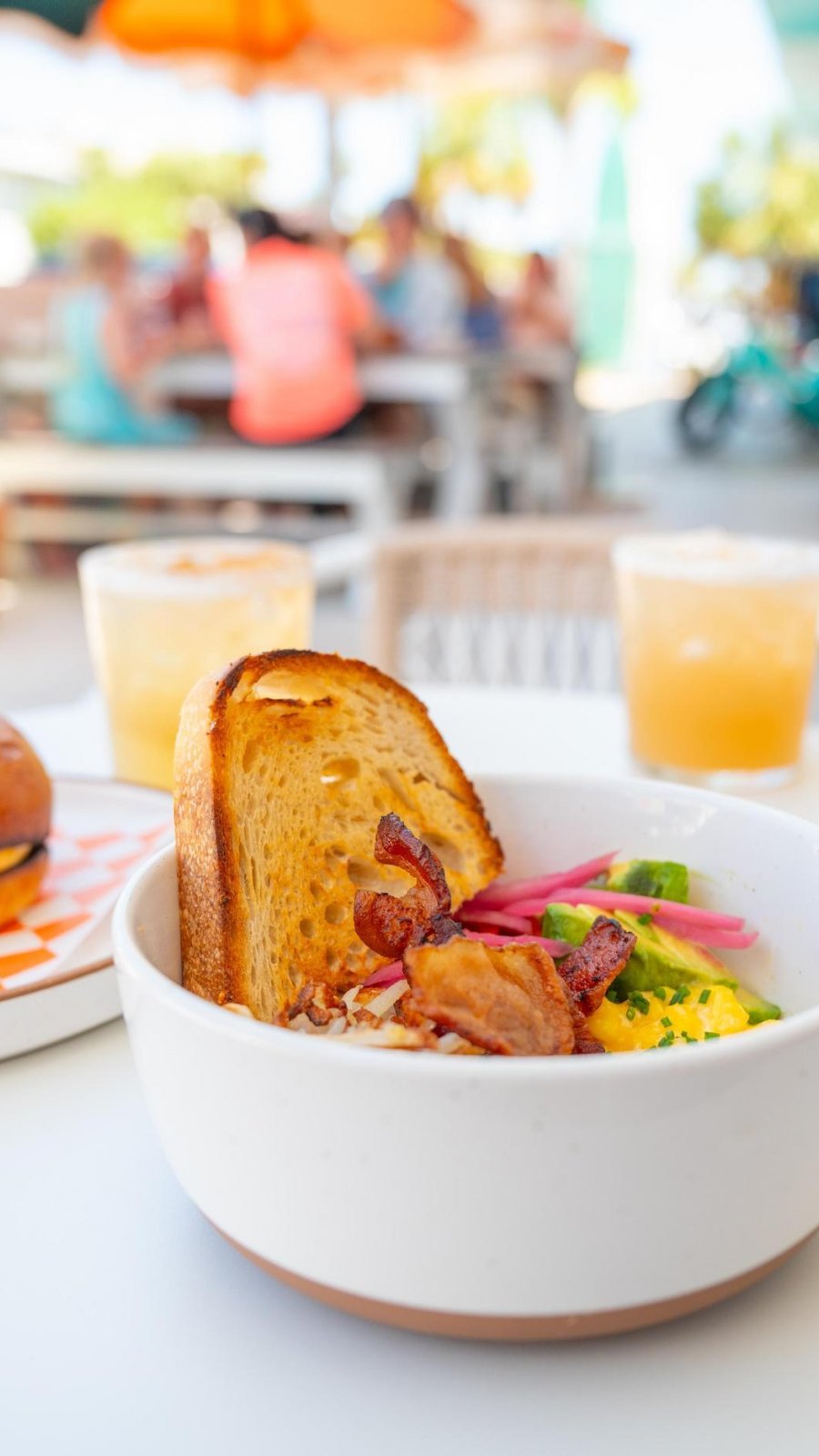 a breakfast bowl with hashbrowns, eggs, bacon and toast next to a breakfast bagel on an outdoor table at Grove Surf Cafe in Indian Rocks Beach