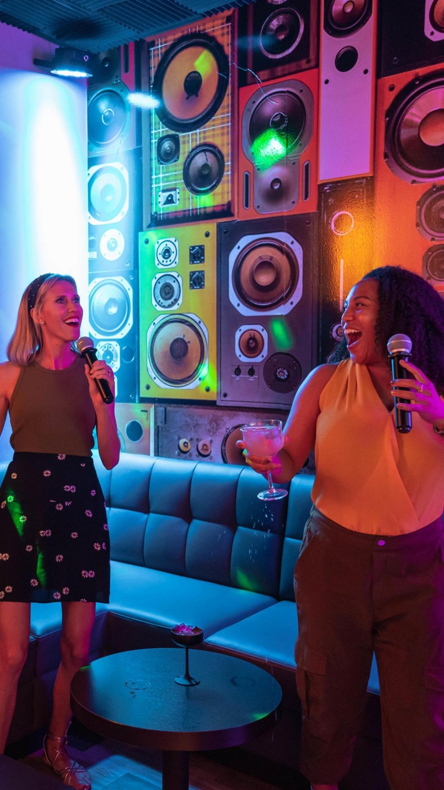 two women singing karaoke in a room lit in neon colors at LaLa in St. Pete