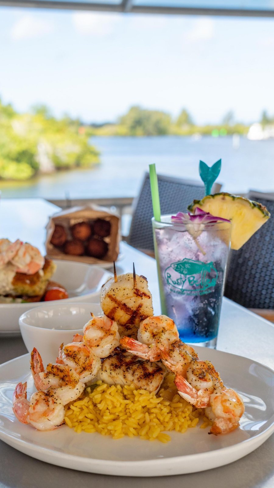 drinks, a salad with fish on top and a plate of rice with shrimp arranged on top at Rusty Bellies Waterfront Grill in Tarpon Springs