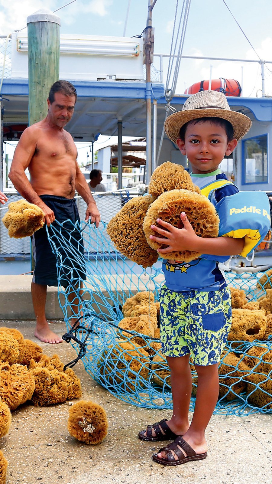 a young boy holds natural sponges near the Tarpon Springs sponge docks
