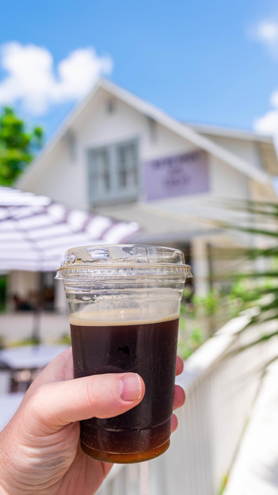 a person's hand holding an iced coffee outside in the patio area at Tukro Coffee in Dunedin, FL