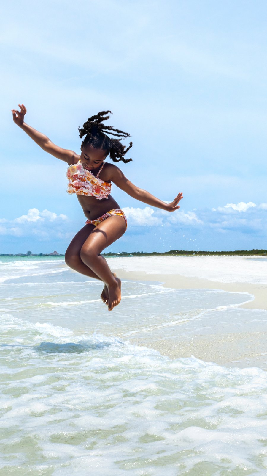 a girl jumping at the water's edge at Fort De Soto Park