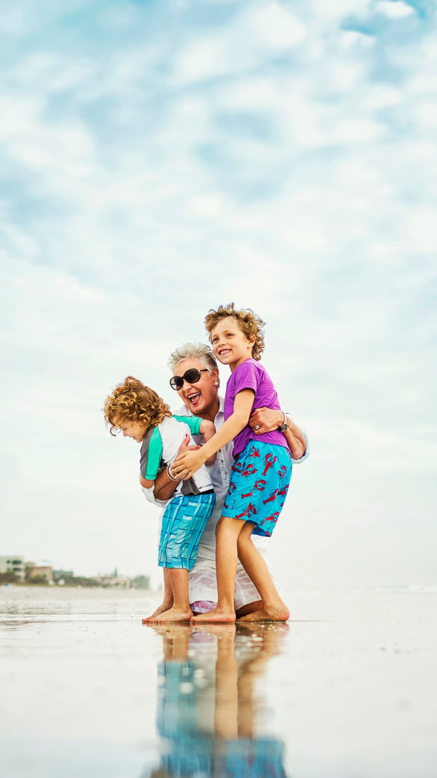 a grandmother playing on the beach with two young children