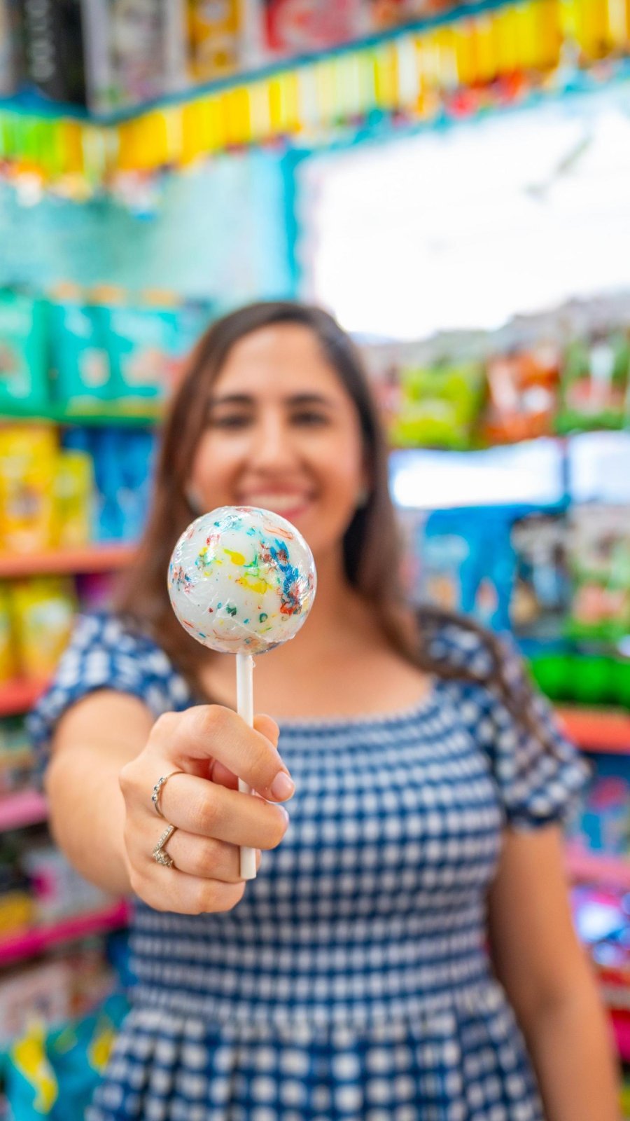 a young woman holding a giant speckled lollipop at Candy Kitchen, a nostalgic candy store in Madeira Beach