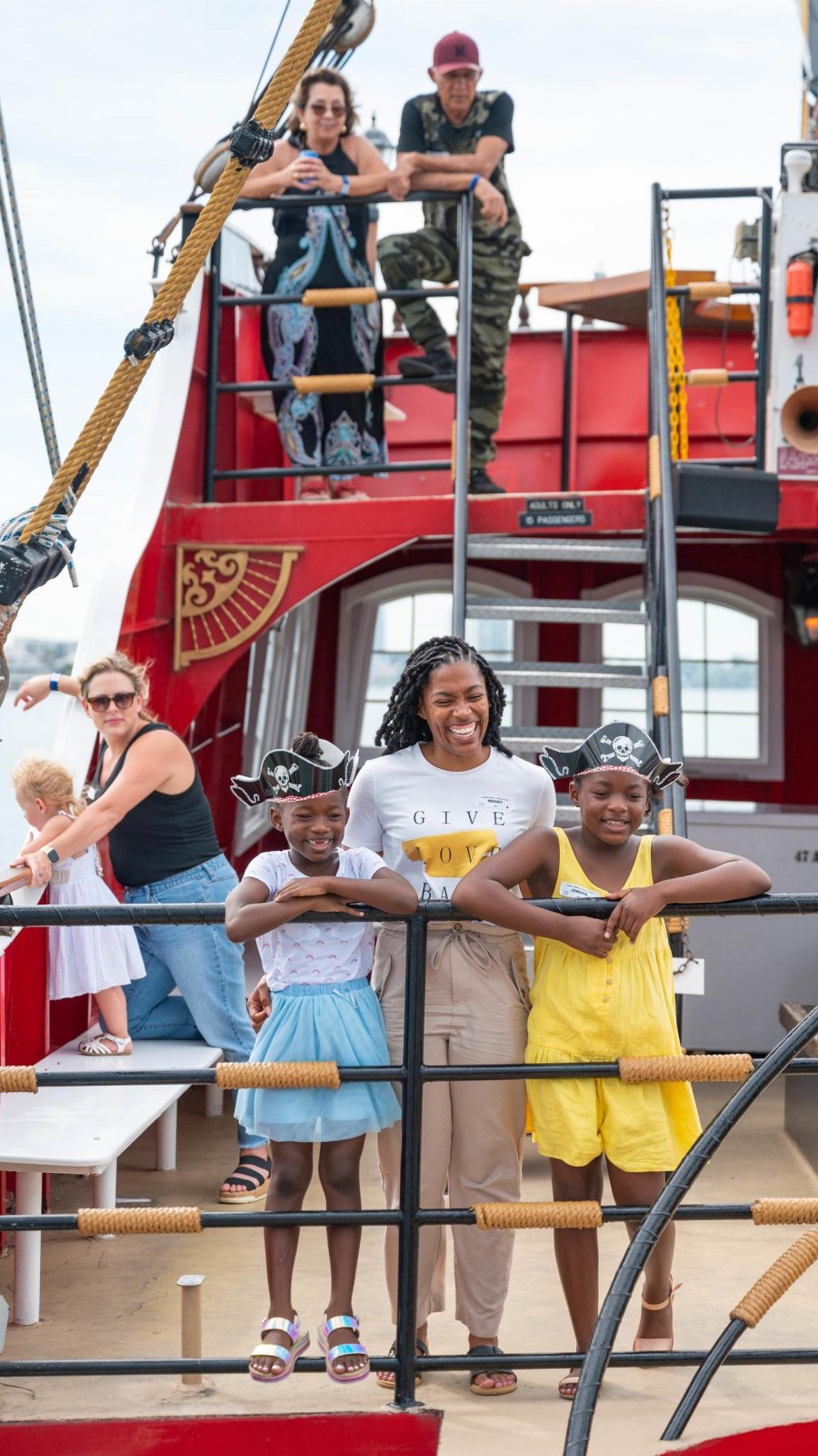two little girls wearing pirate hats with their mom on the top deck of Captain Memo's Pirate Cruise