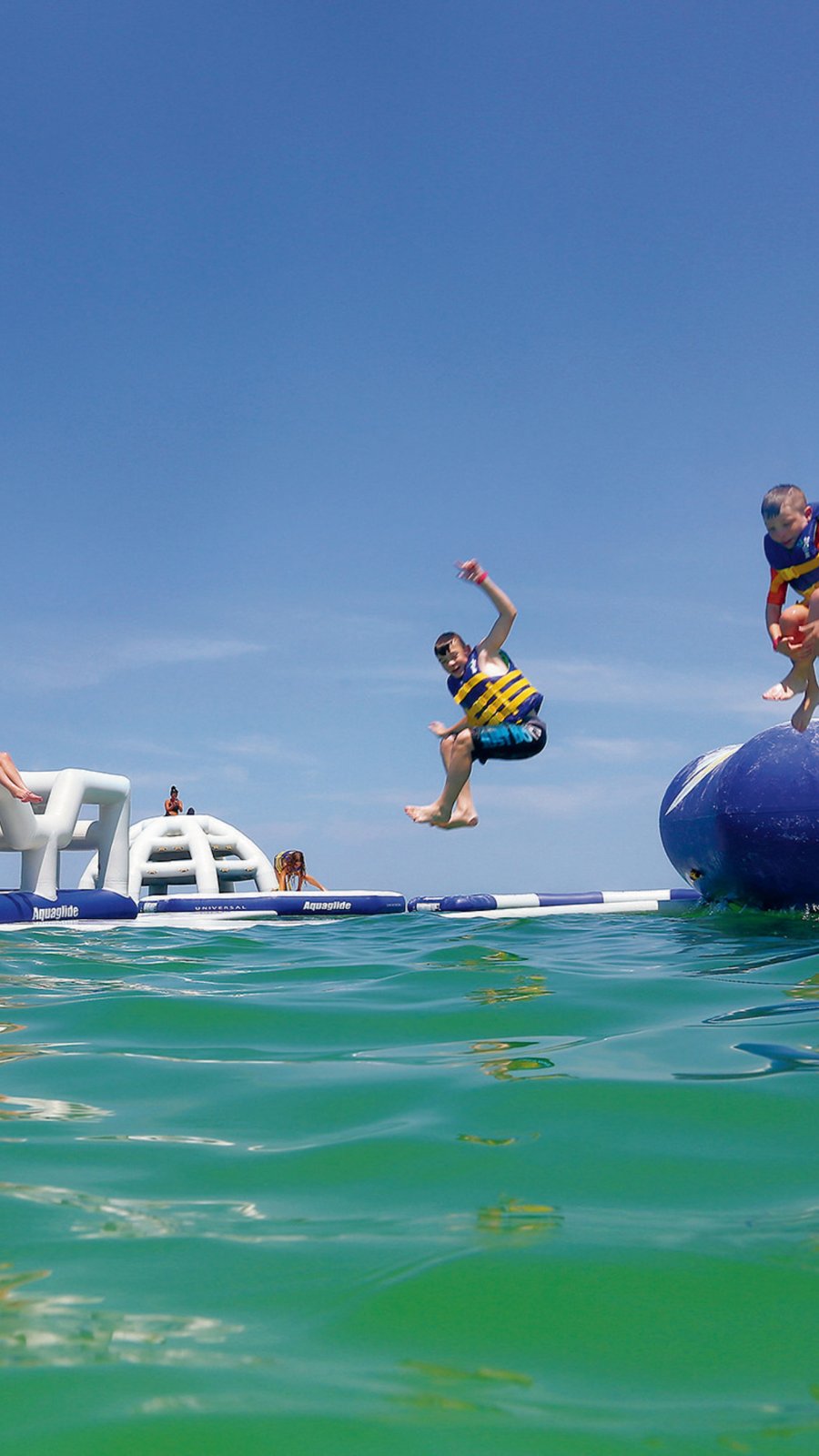 kids jumping off an inflatable water park in the Gulf at TradeWinds Resort in St. Pete Beach